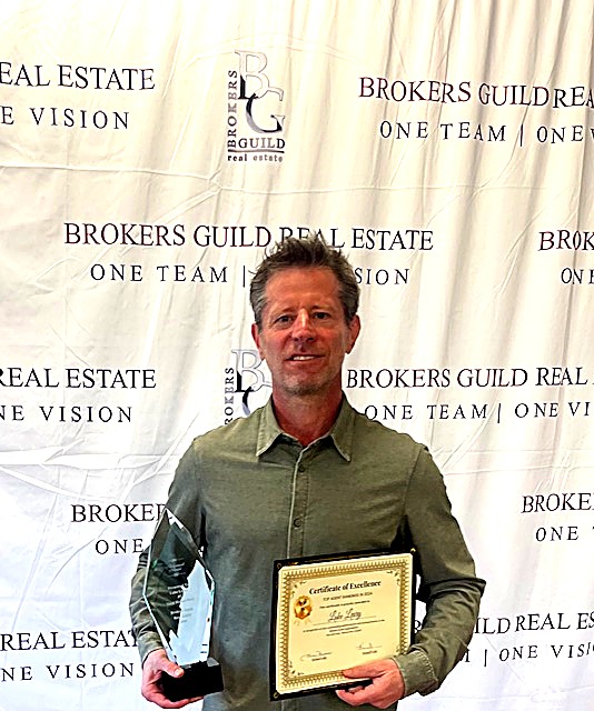 Luke Leary - Award-winning Denver Realtor holding #1 Agent trophy and certificate at Broker's Guild Real Estate